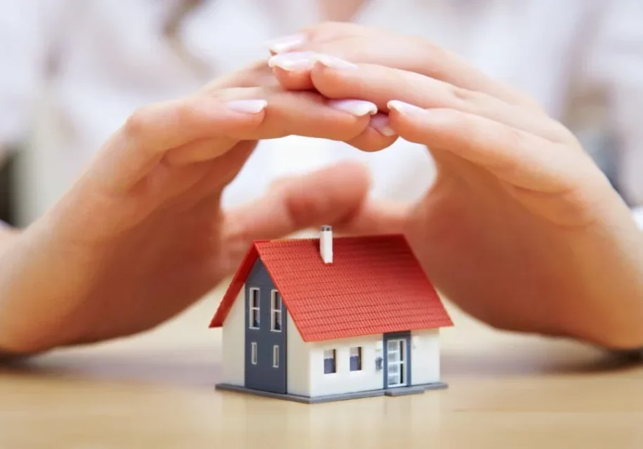 A person is holding their hands over the roof of a house.