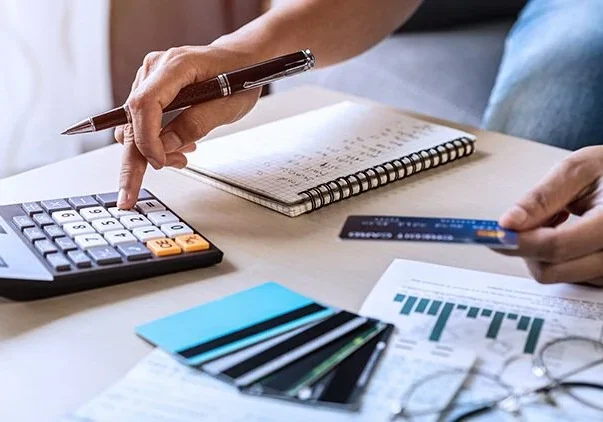 A person is using a calculator to calculate their credit card bill.